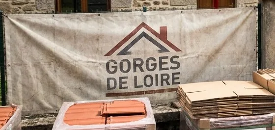 Bâche de chantier au logo Gorges de Loire, couvreur à Saint-Just-Saint-Rambert, tendue devant une maison pendant les travaux de toiture